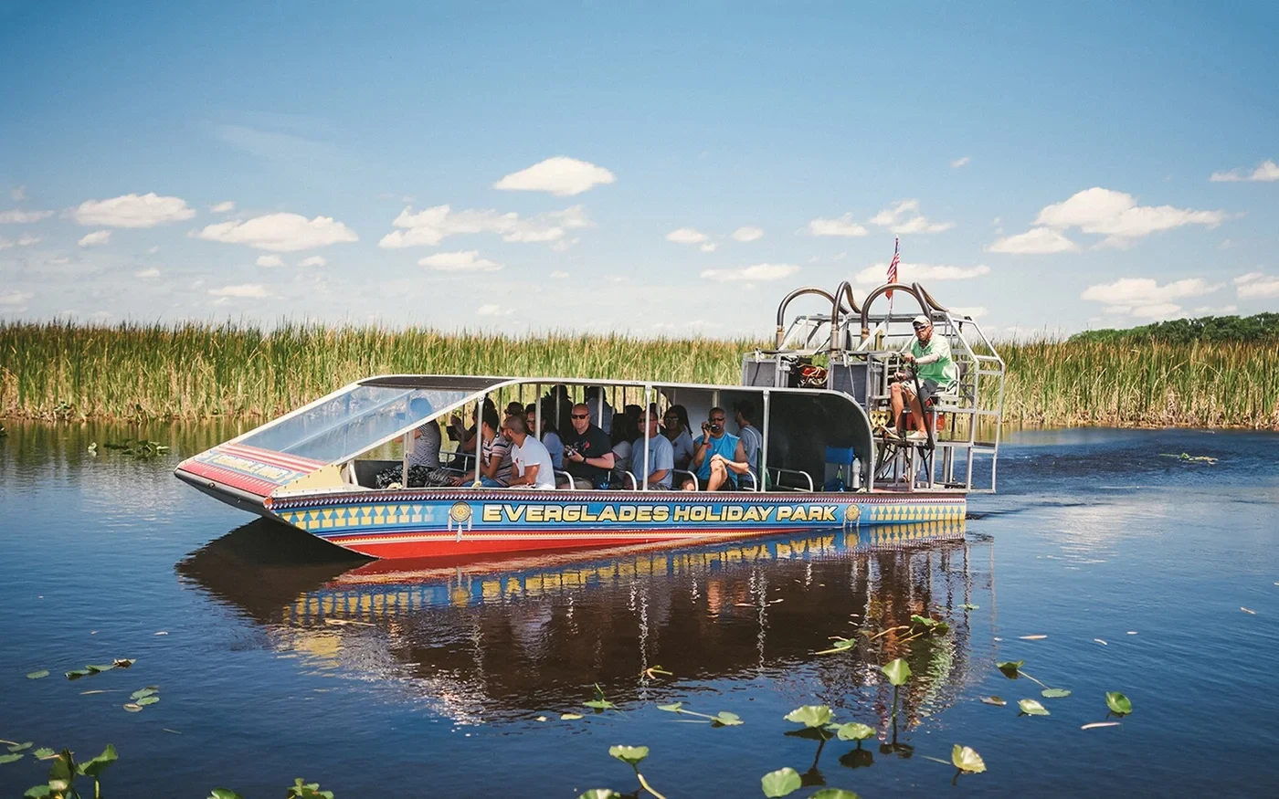 Passenger airboat on water surrounded by wetland grasses