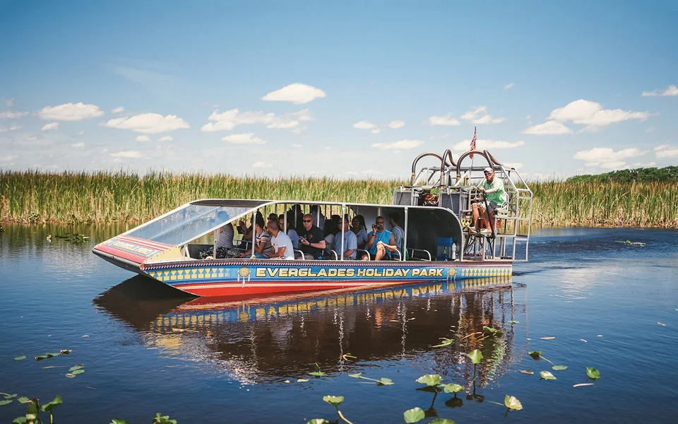 Passenger airboat on water surrounded by wetland grasses