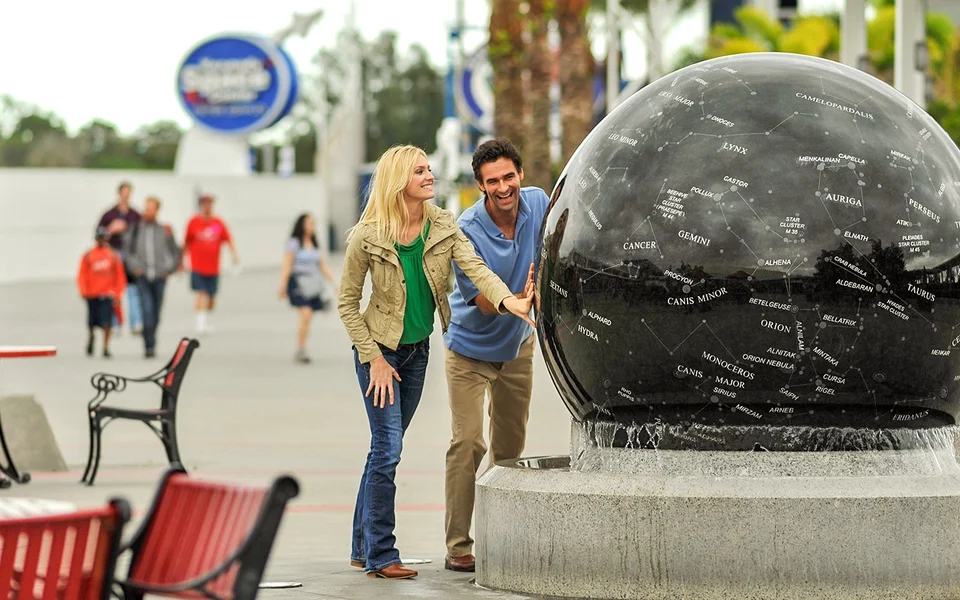 Visitors studying a dark spherical exhibit at Kennedy Space Center